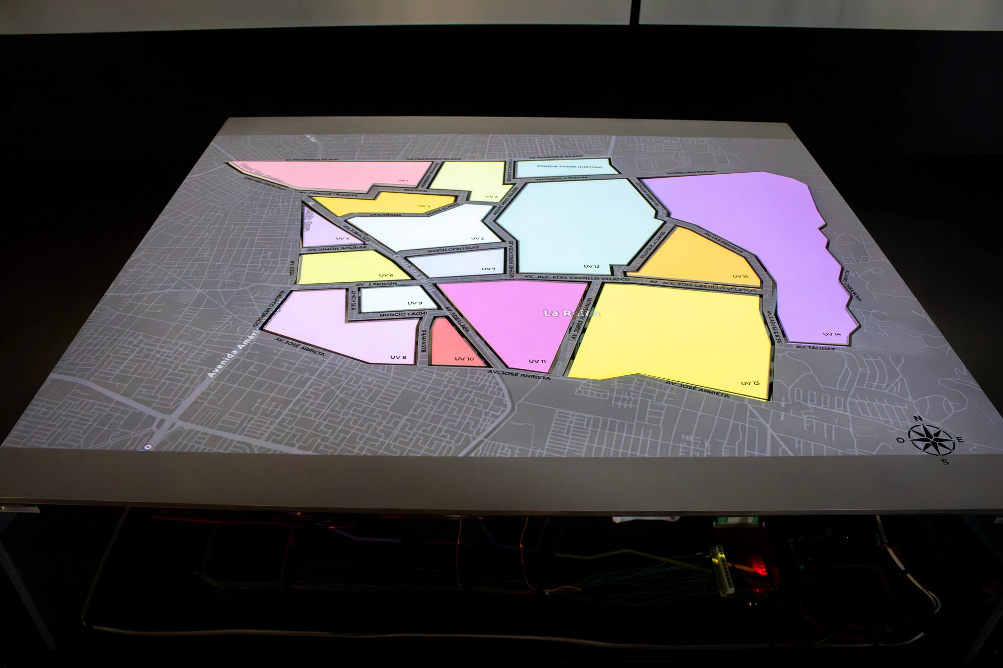 Mesa interactiva con el mapa de La Reina dividido en unidades vecinales iluminadas por color